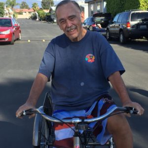 Dan Brolliar, Jr. Riding a bicycle and wearing a Camp Emerald Bay T-Shirt