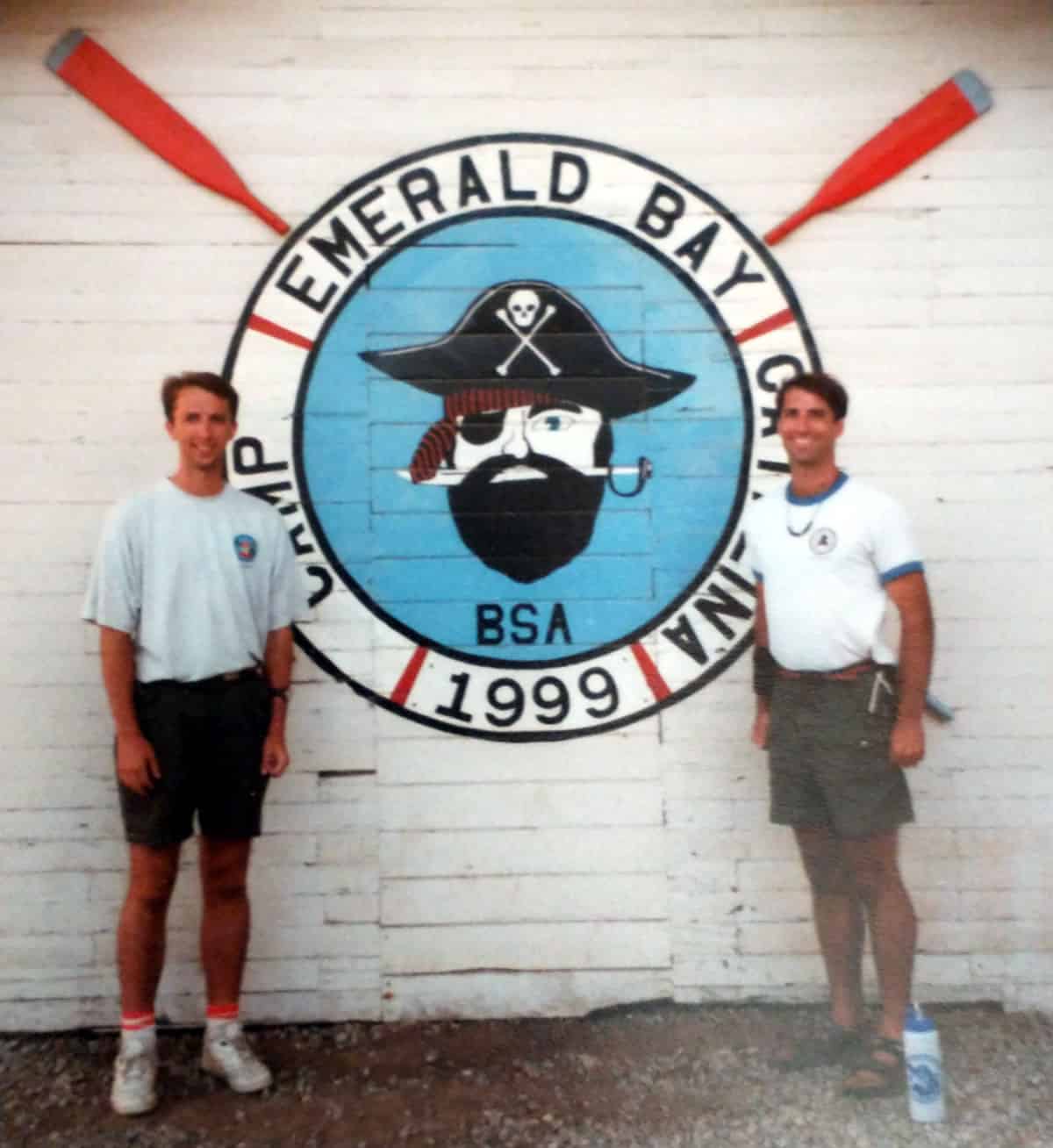 David and Scott standing in front of the Staff Logo on the side of the Boathouse in 199