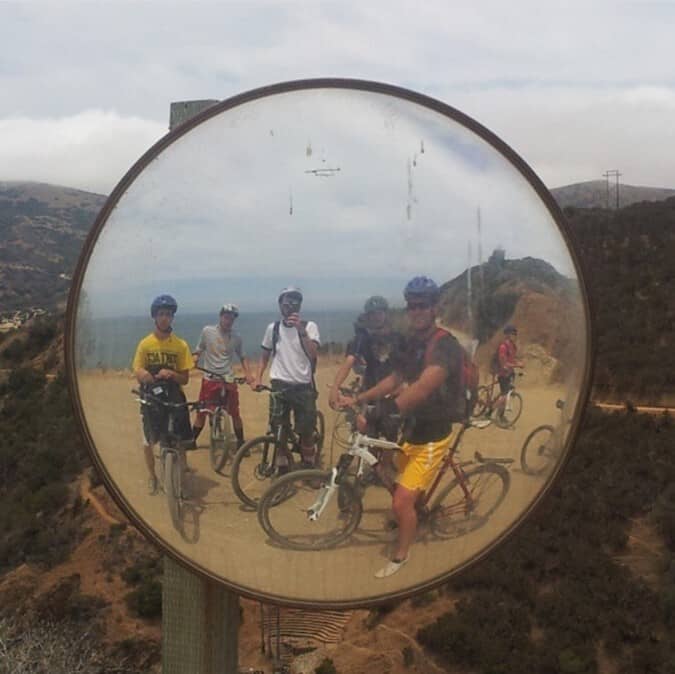 Eric and friends biking on Catalina, taking a selfie inside a parabolic mirror along the road.